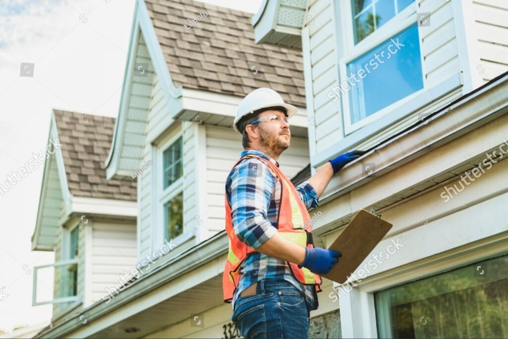 imgi 1 stock photo a man with hard hat standing on steps inspecting house roof 2361106567