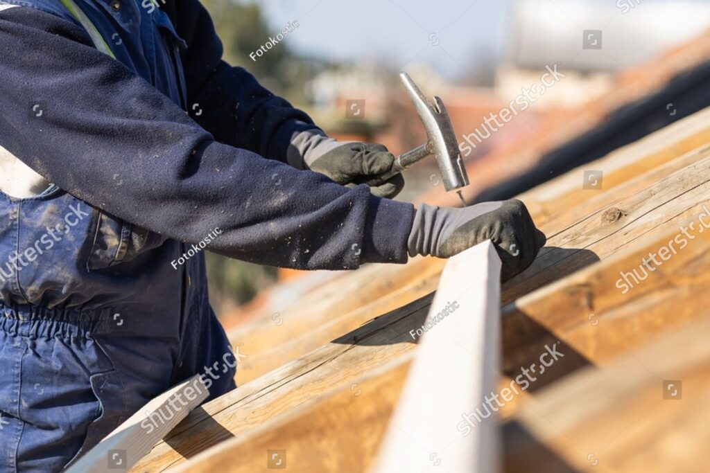imgi 1 stock photo construction roofer carpenter worker nailing wood board with hammer on roof installation work 2591142501